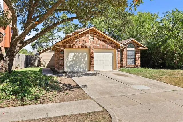 a view of a house with a yard plants and large tree