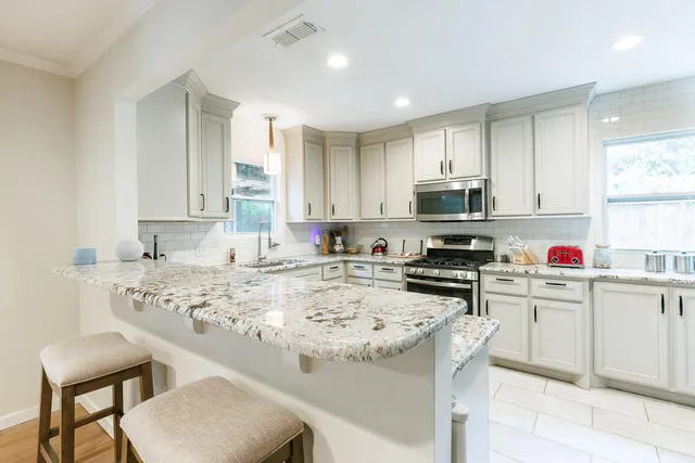 a kitchen with granite countertop a sink stainless steel appliances and white cabinets