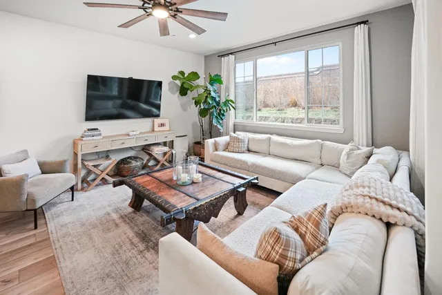 a living room with furniture a flat screen tv and a large window