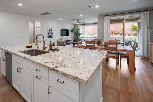 a kitchen with granite countertop a stove a sink a dining table and chairs