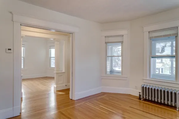 a view of an empty room with wooden floor and a window