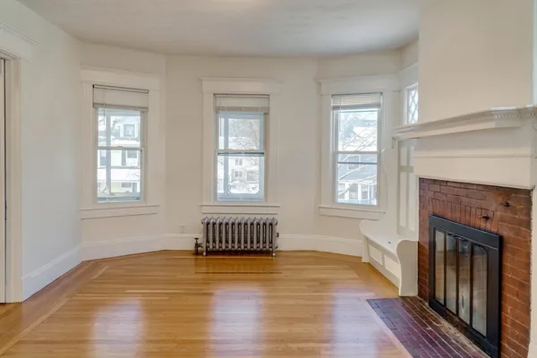 a living room with wooden floor and a fireplace
