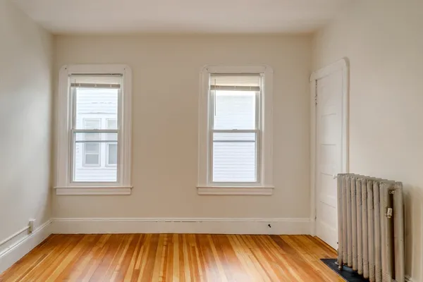 an empty room with a window and wooden floor