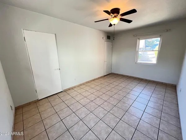 an empty room with windows and fan