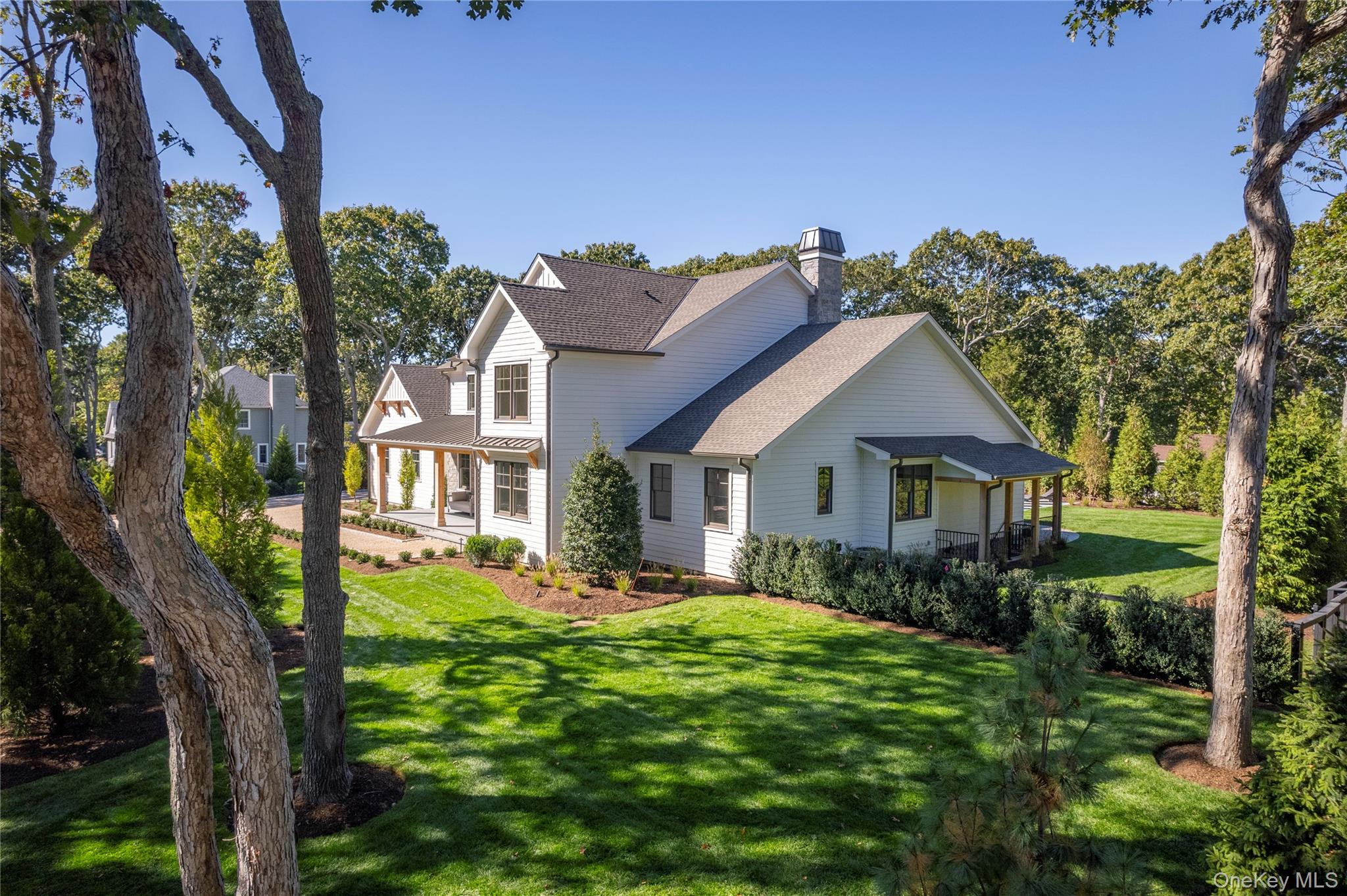 465 Ripple Water Lane Southold, NY 11971 - Photo 11 of 46 Back of property featuring a lawn, a porch, a chimney, and roof with shingles