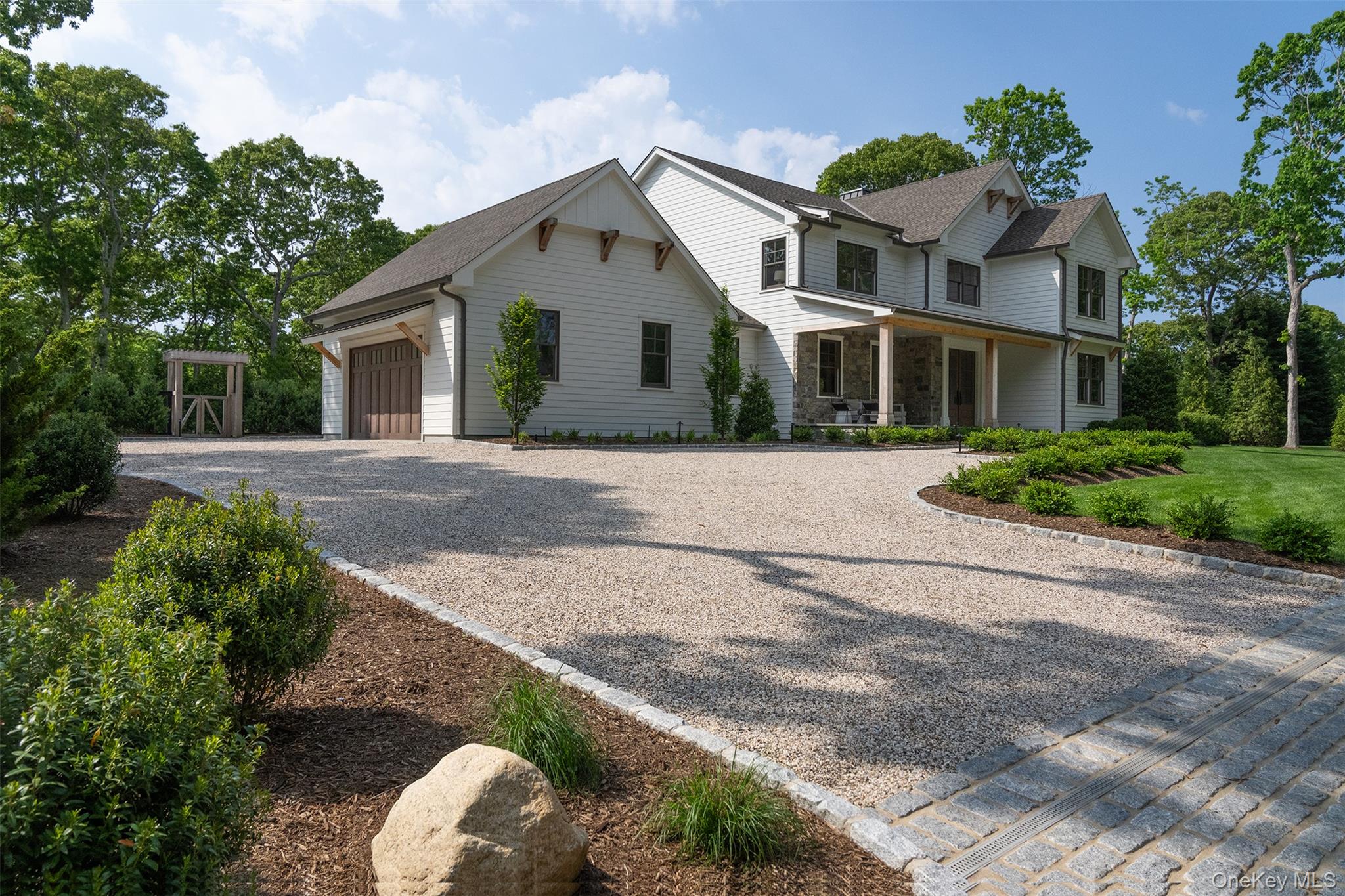 465 Ripple Water Lane Southold, NY 11971 - Photo 16 of 47 View of front of property featuring driveway, an attached garage, stone siding, and roof with shingles