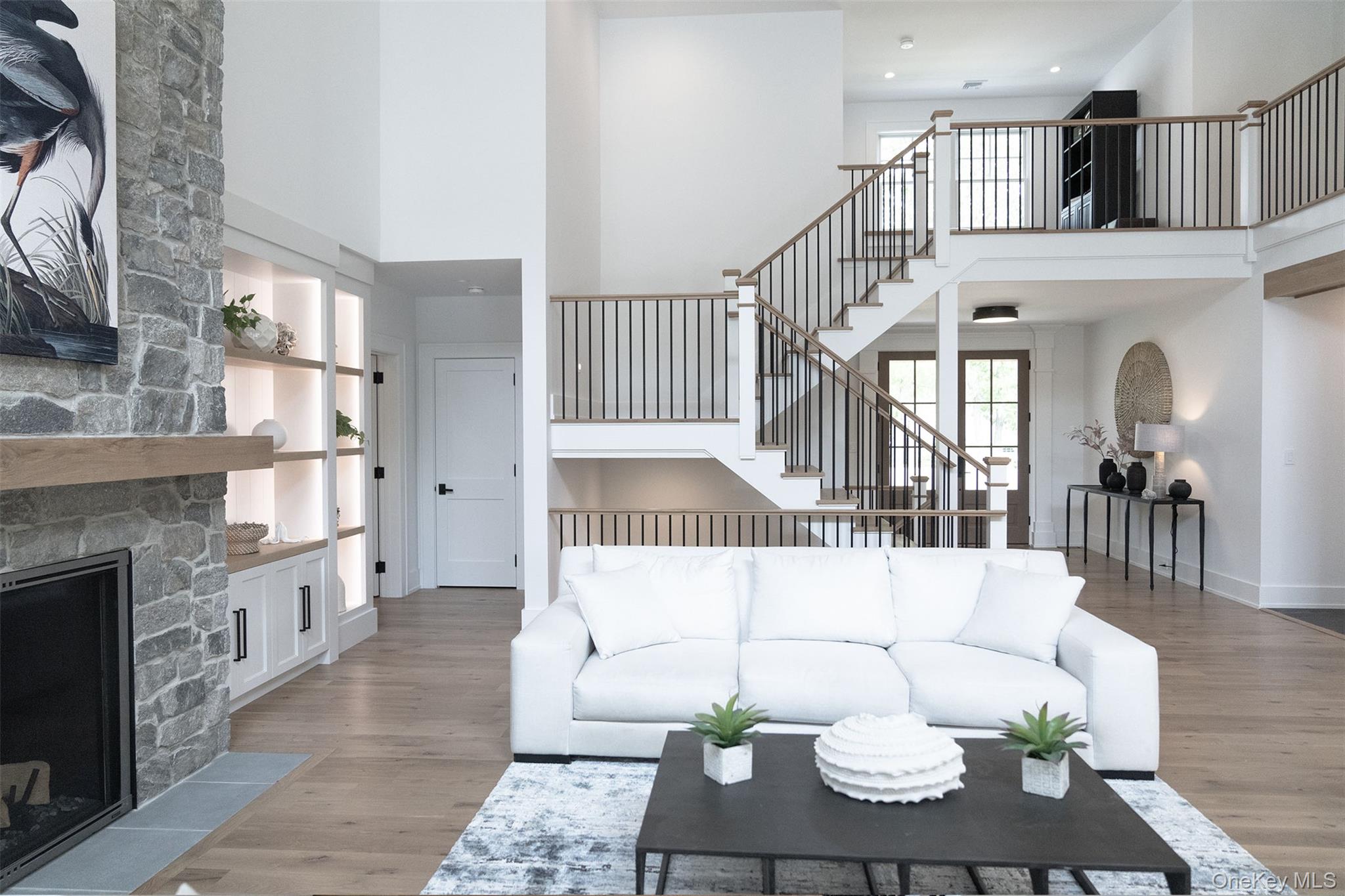 465 Ripple Water Lane Southold, NY 11971 - Photo 37 of 47 Living area with a high ceiling, a stone fireplace, wood finished floors, stairway, and built in features