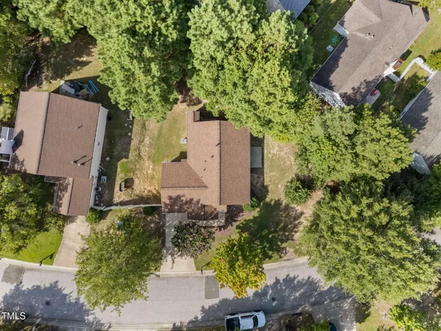 an aerial view of a house with a yard and large trees