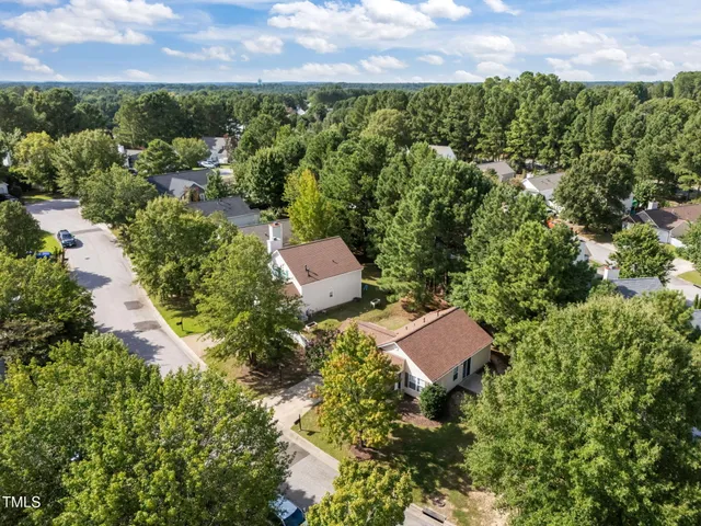 an aerial view of residential house with outdoor space and trees all around