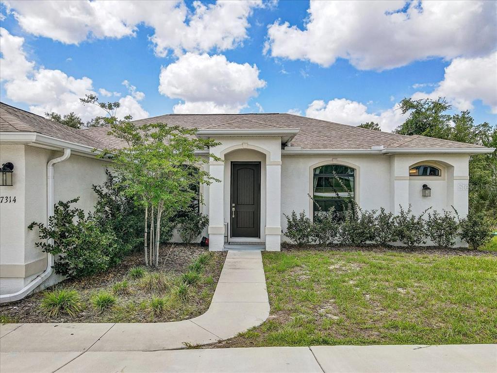 7314 Madrid Road Weeki Wachee, FL 34613 - Photo 3 of 54 front view of a house with a yard