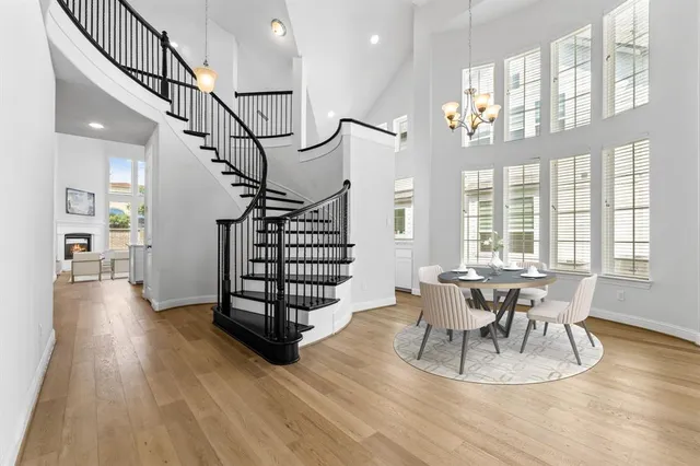 a dining room with wooden floor a chandelier a glass table and chairs