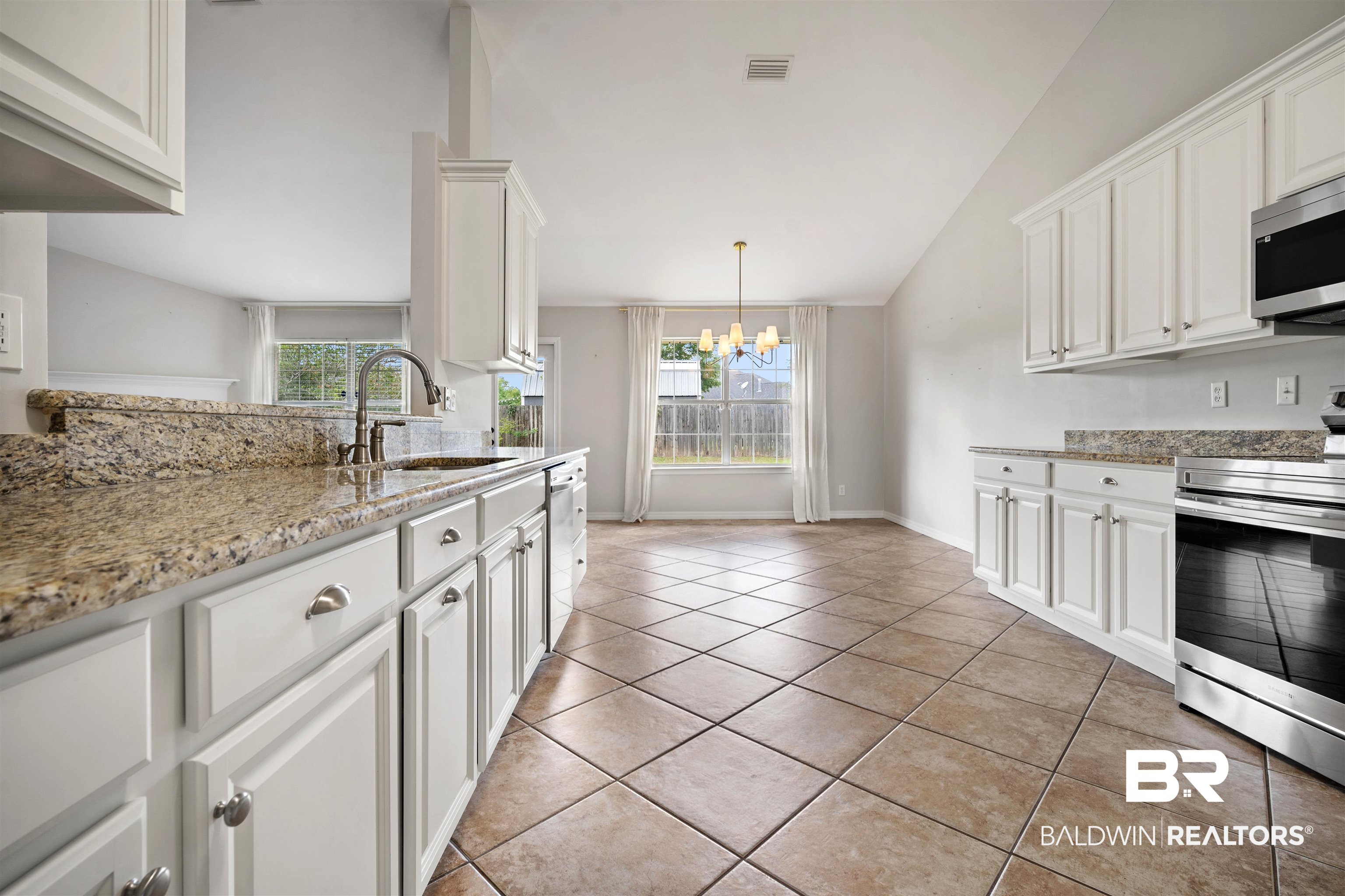 4000 Fenwick Loop Mobile, AL 36619 - Photo 8 of 31 Kitchen featuring appliances with stainless steel finishes, a chandelier, healthy amount of natural light, white cabinets, and lofted ceiling