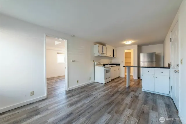 an empty room with wooden floor mirror and windows
