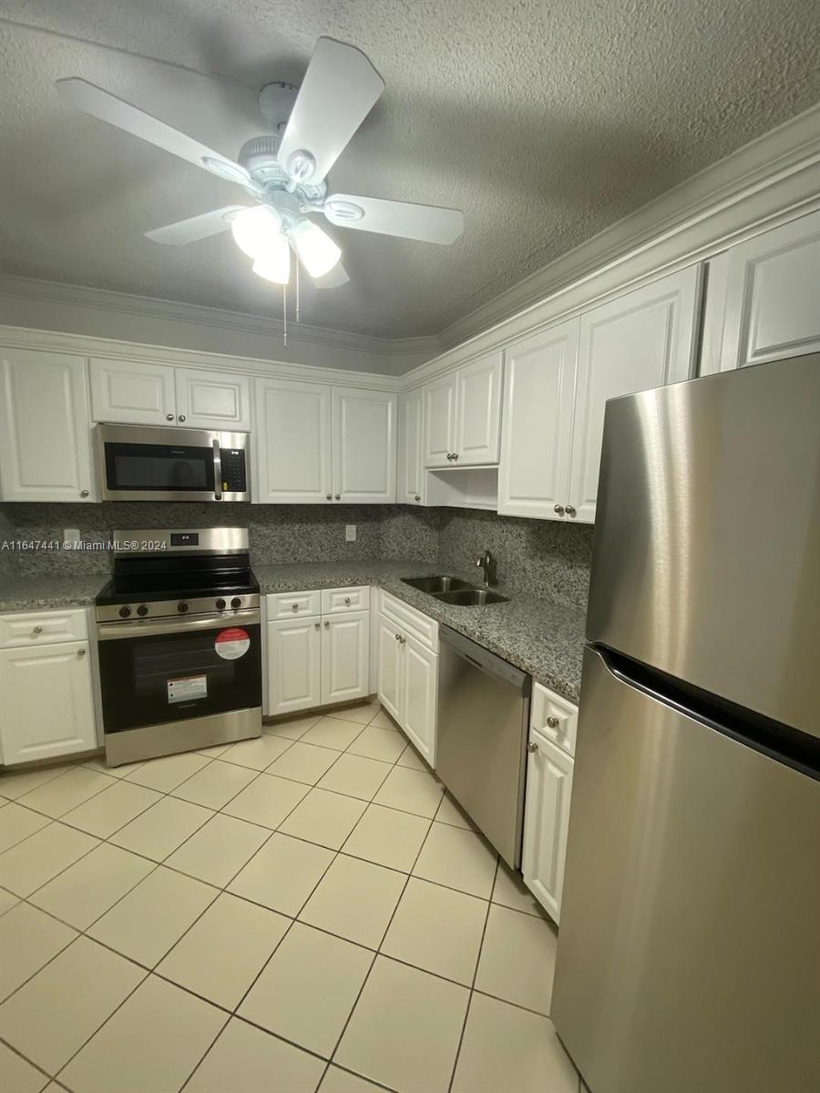 3850 Washington Street, Unit 1110 Hollywood, FL 33021 - Photo 3 of 29 a kitchen with granite countertop a refrigerator a sink and white cabinets