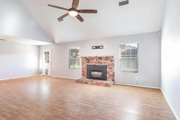 an empty room with windows fireplace and a kitchen view
