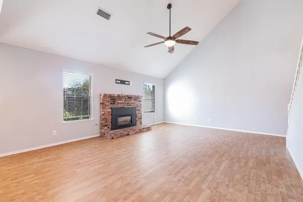 an empty room with wooden floor fireplace and windows