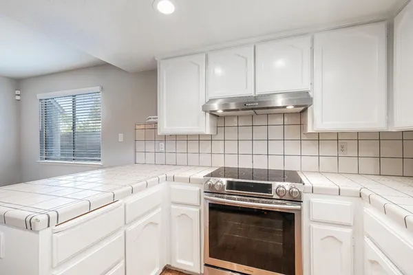 a kitchen with a stove top oven and cabinets