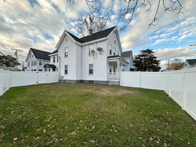a view of a white house with a big yard with large tree