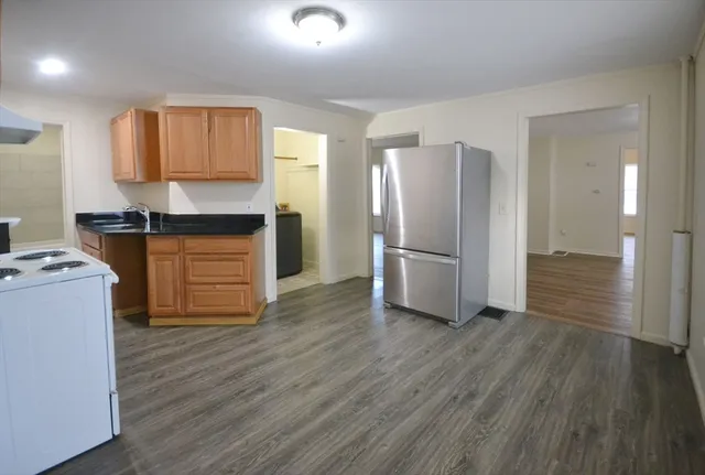 a kitchen with granite countertop a refrigerator and a stove top oven