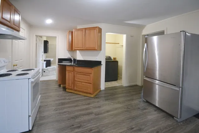 a kitchen with granite countertop a refrigerator and a stove top oven