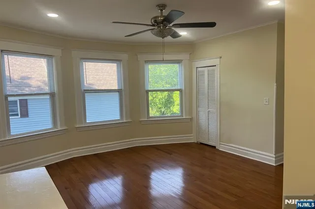 an empty room with wooden floor fan and windows