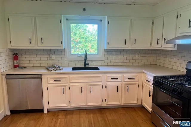 a kitchen with granite countertop white cabinets and a stove