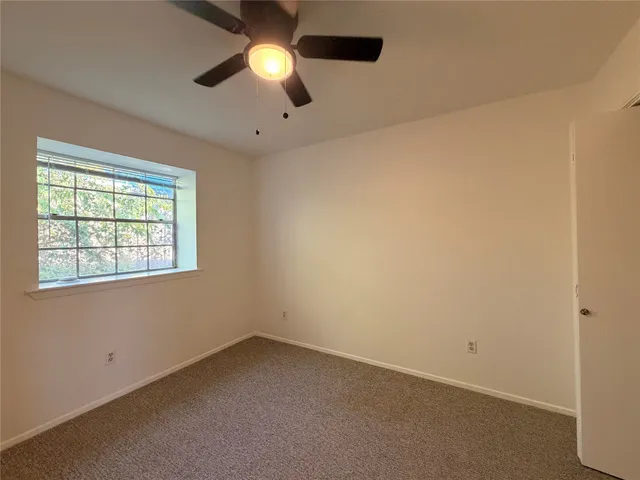 an empty room with a window and a fan