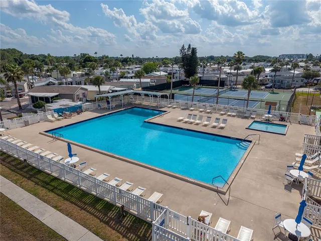 a view of a pool with lawn chairs and plants