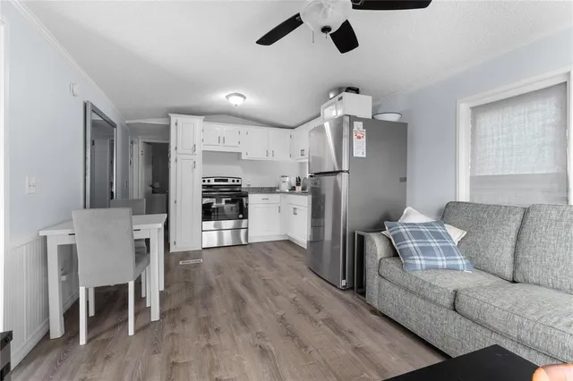 a living room with stainless steel appliances furniture a dining table and chairs