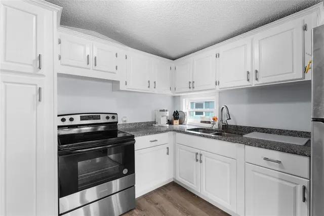 a kitchen with granite countertop white cabinets and stainless steel appliances