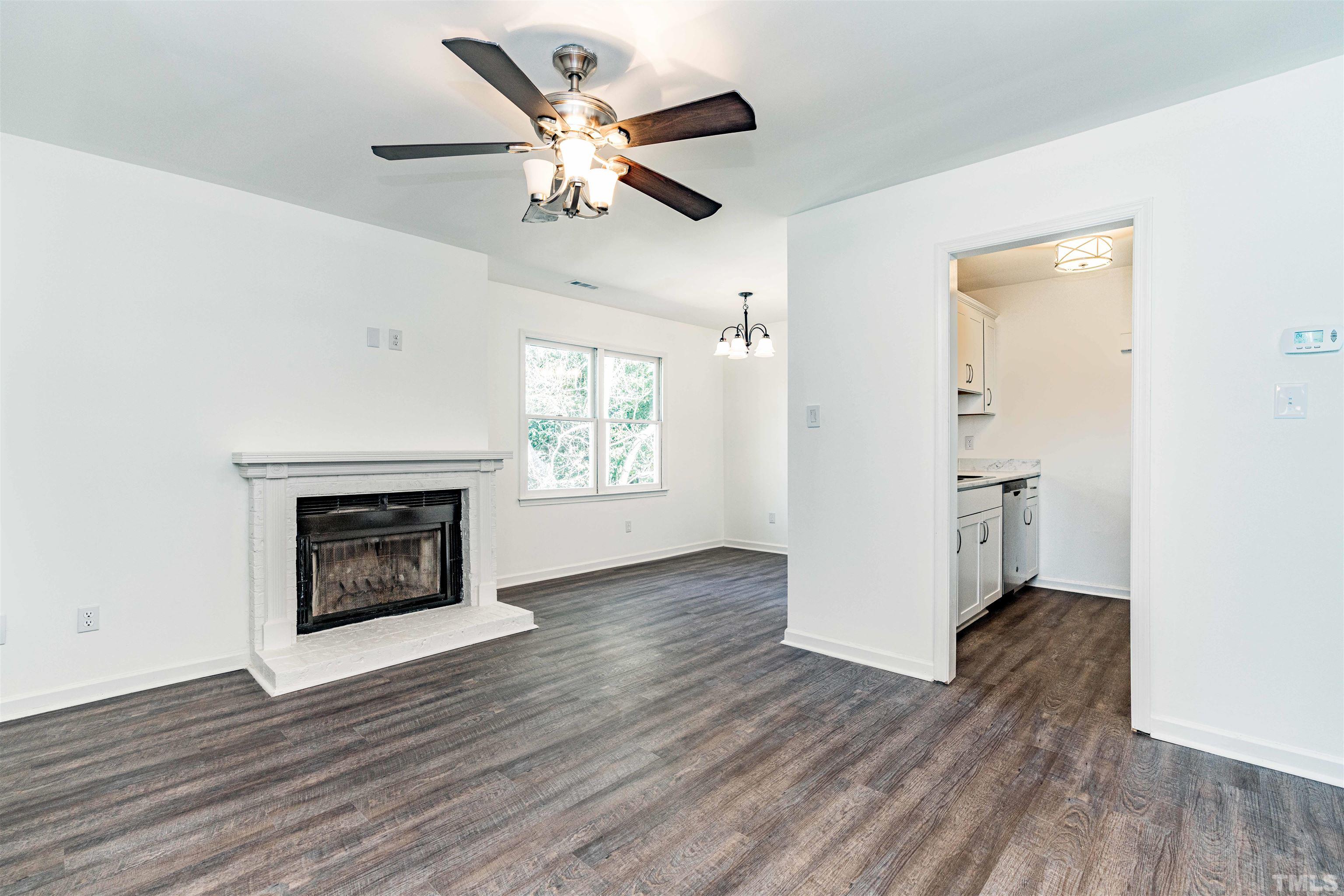 3643 Mill Run, Unit 3643 Raleigh, NC 27612 - Photo 5 of 25 an empty room with wooden floor a ceiling fan and a fireplace