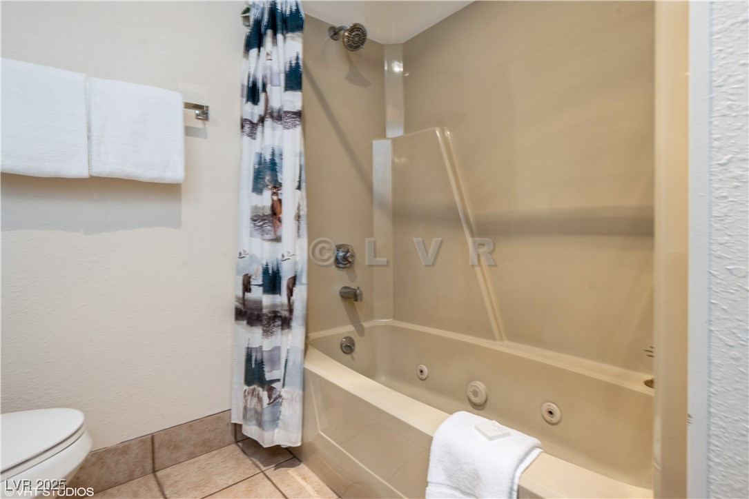 223 Hunter Ridge Drive, Unit 300 Brian Head, UT 84719 - Photo 15 of 48 Bathroom featuring tile patterned flooring, toilet, and a combined bath / shower with jetted tub