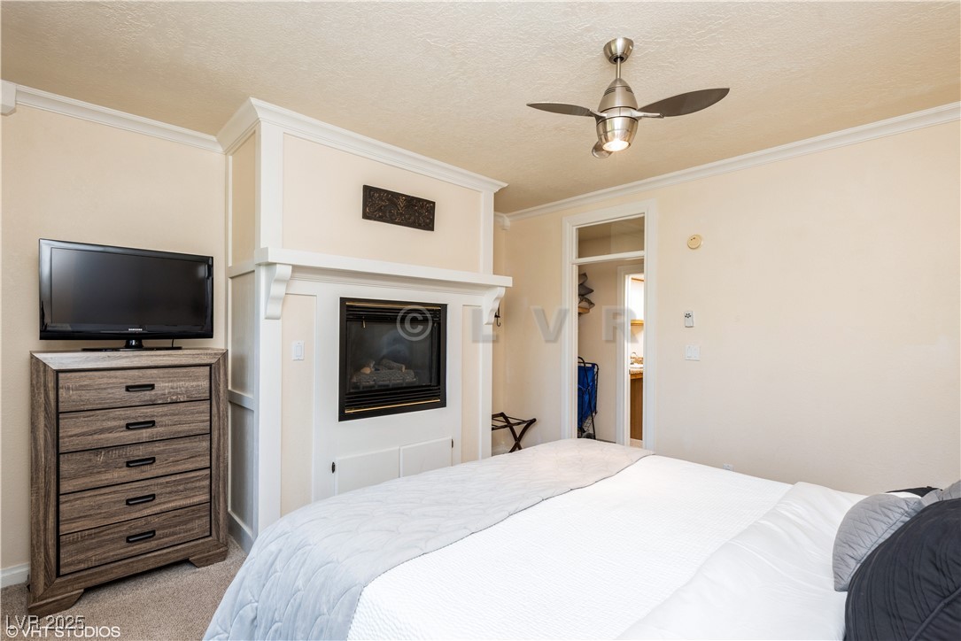 223 Hunter Ridge Drive, Unit 300 Brian Head, UT 84719 - Photo 21 of 48 Bedroom with light carpet, crown molding, a glass covered fireplace, and a textured ceiling