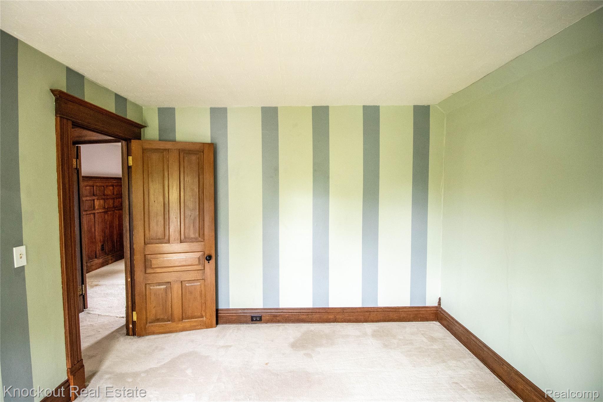 19983 West Ridge Road Henderson, MI 48841 - Photo 42 of 76 Room featuring striped accent wall, wood-finish trim, and a paneled wood door