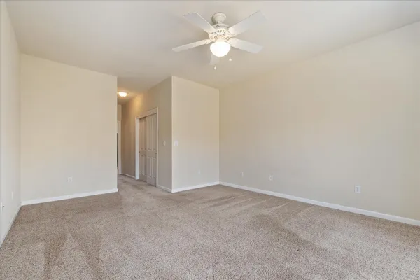 an empty room with a ceiling fan and a window