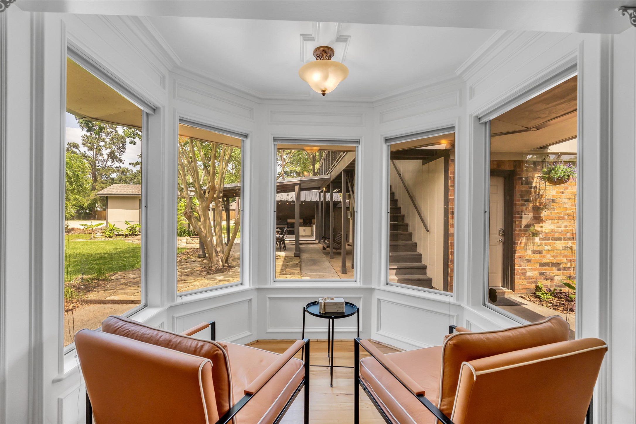 22502 Fields Lane Spring, TX 77389 - Photo 8 of 39 Cozy bay window nook, featuring two modern leather chairs and a small table. The large windows provide a bright view of the landscaped backyard, creating an inviting space for relaxation.