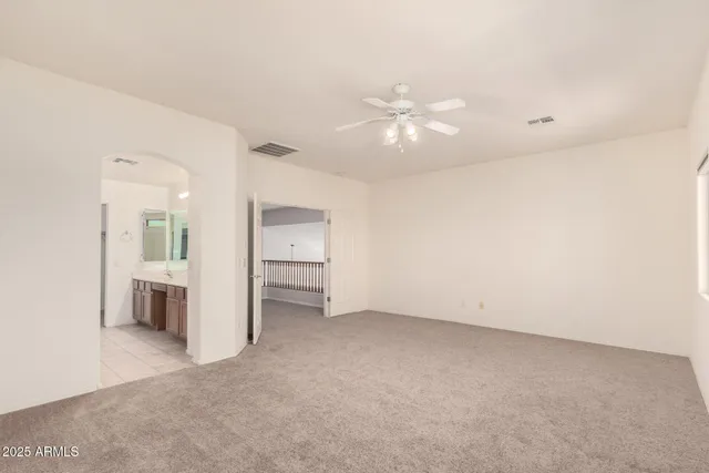 an empty room with chandelier fan and windows