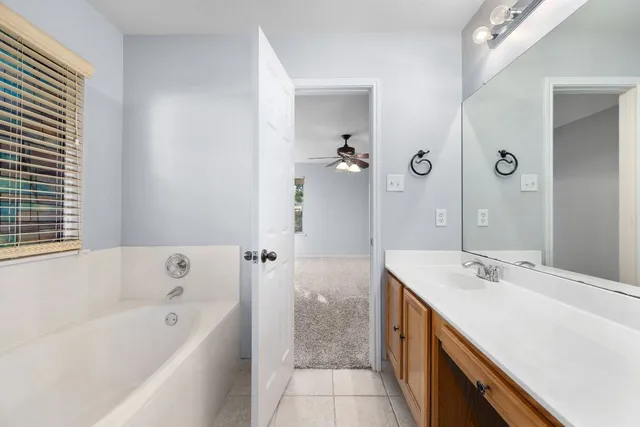 a bathroom with a tub a sink and mirror