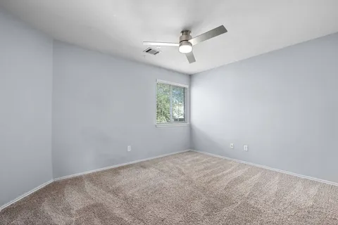 an empty room with a window and ceiling fan