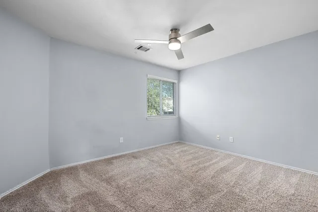 an empty room with a window and ceiling fan