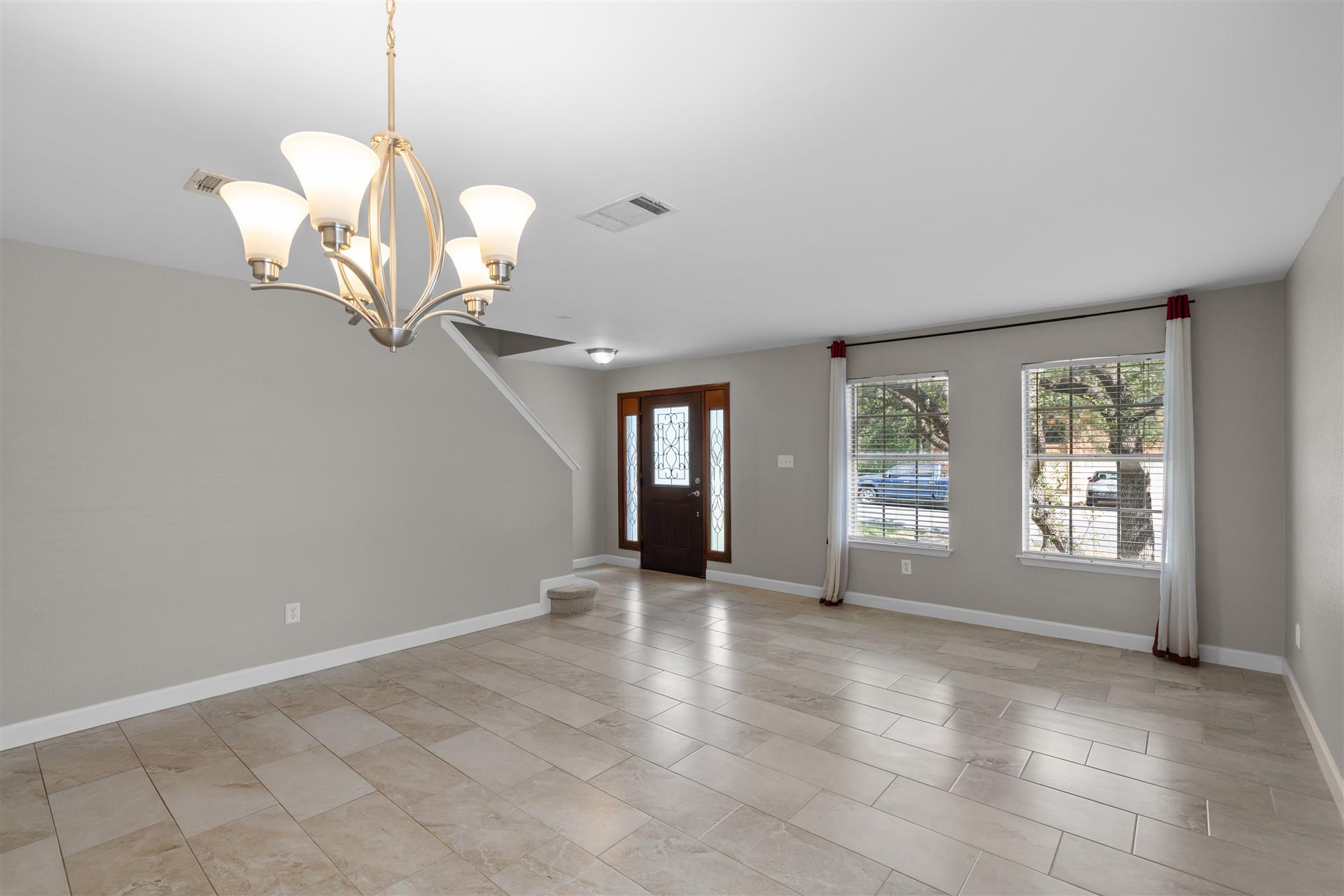 1710 Persimmon Road Cedar Park, TX 78613 - Photo 10 of 33 A graceful chandelier illuminates the combined dining room and living room with durable tile flooring and welcoming front entry.