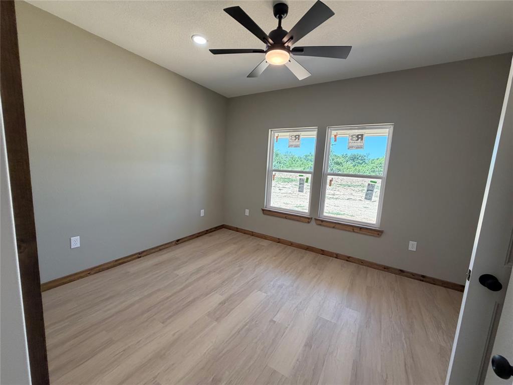 1040 Rays Way Weatherford, TX 76085 - Photo 15 of 23 Bright room featuring two large windows, wood-finish flooring, a contemporary ceiling fan with integrated lighting, recessed lighting, and neutral wall tones