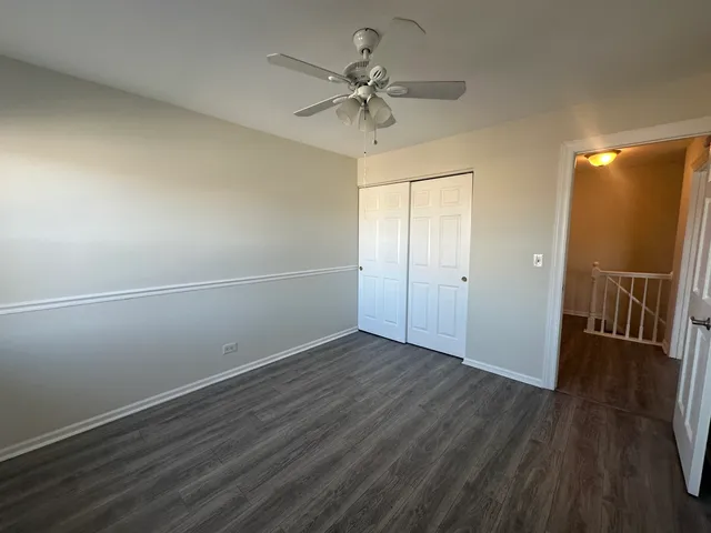 an empty room with wooden floor and fan