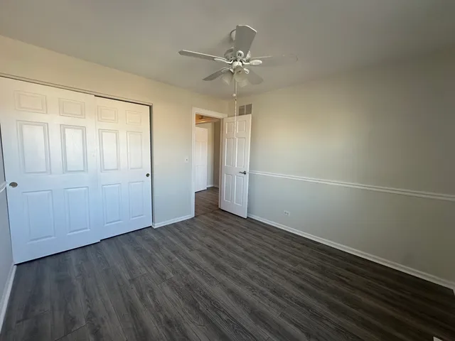 an empty room with wooden floor fan and windows