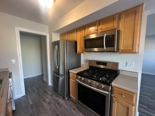 a kitchen with granite countertop a refrigerator and a stove top oven