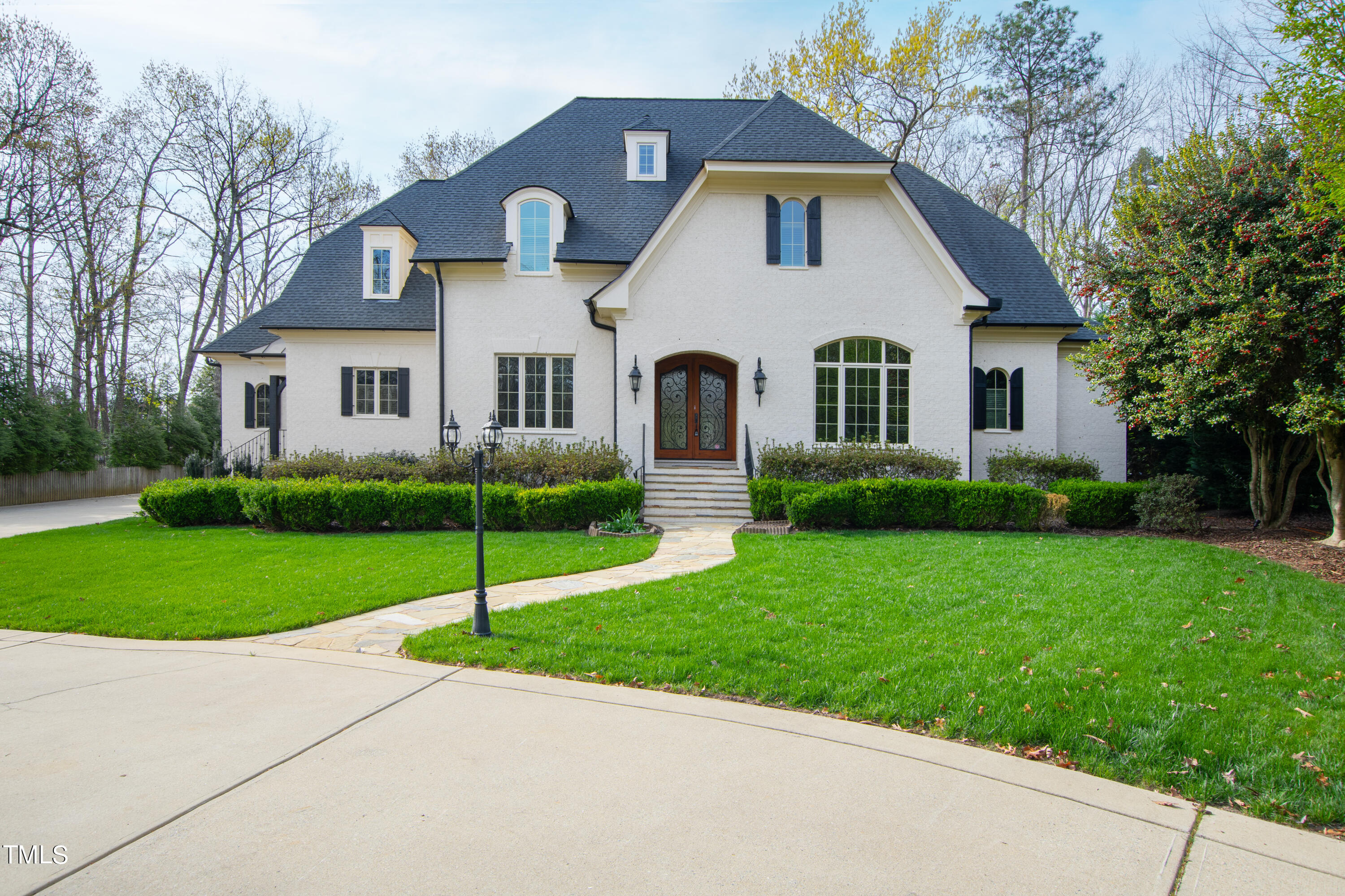 a front view of a house with a garden and trees