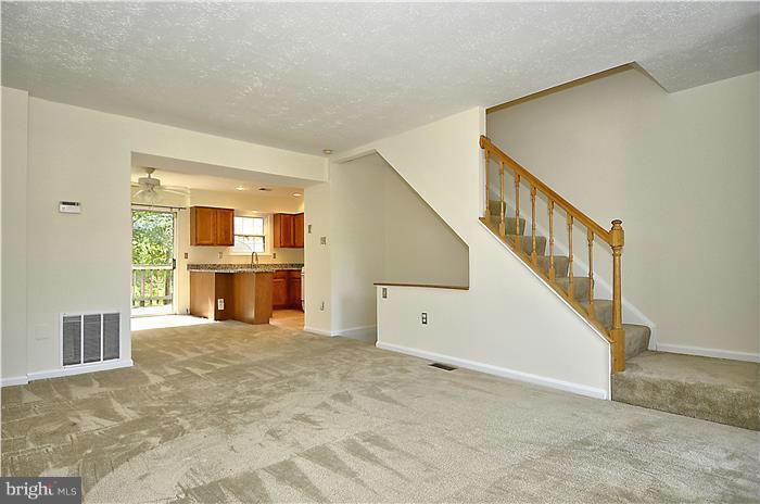 515 Pickwick Village Way Silver Spring, MD 20901 - Photo 10 of 20 a view of a hallway with an empty room and kitchen with fireplace ceiling fan and windows