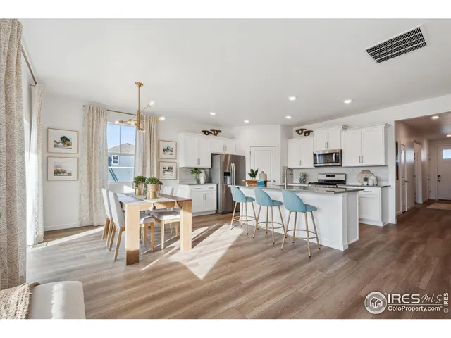 a kitchen with a dining table chairs wooden floor cabinets and stainless steel appliances