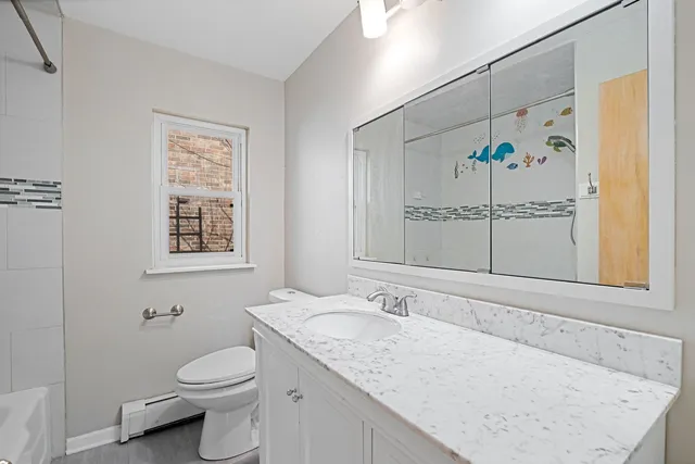 a bathroom with a granite countertop sink mirror vanity and toilet