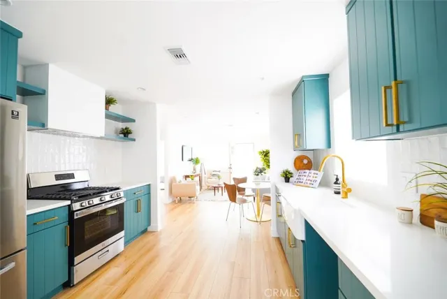 a kitchen with stainless steel appliances a stove a sink dishwasher and cabinets with wooden floor